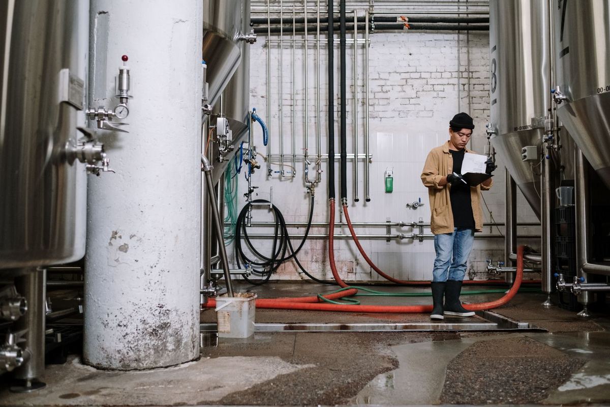 Worker filling in a paper checklist on a clipboard between plant tanks